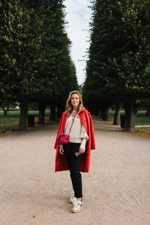 red wool coat cream embroidered sweater sneakers