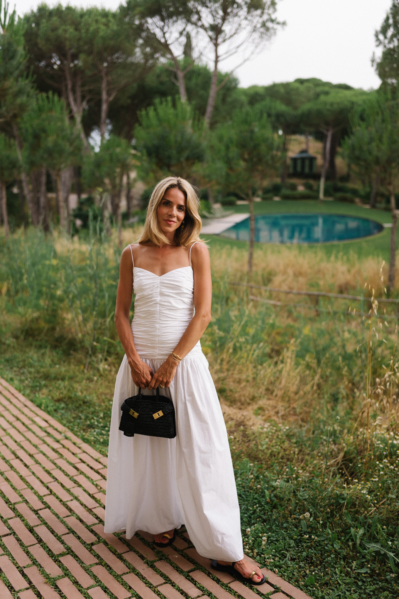 White maxi dress, black leather sandals, black straw bag