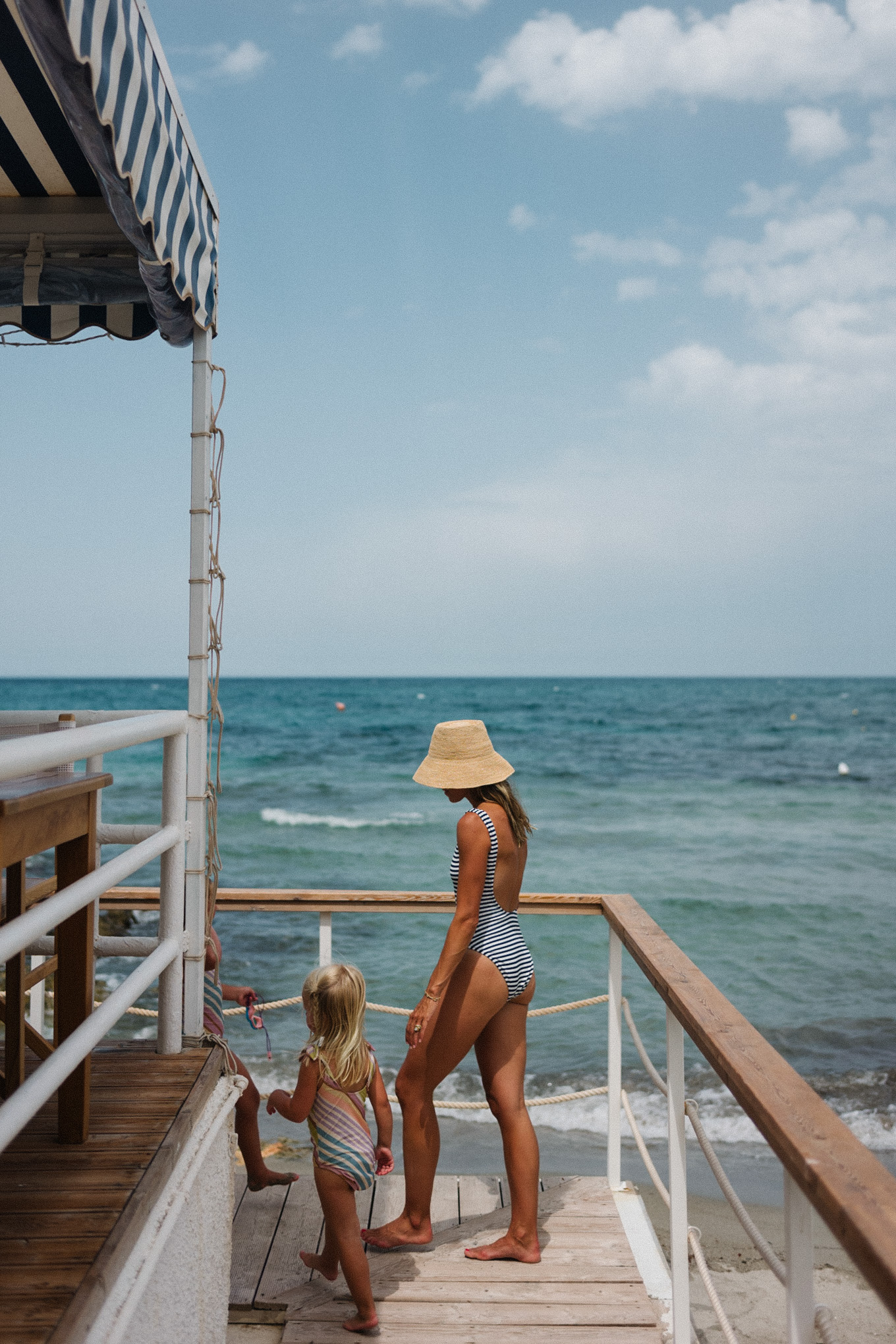 navy white striped swimsuit straw bucket hat white sunglasses