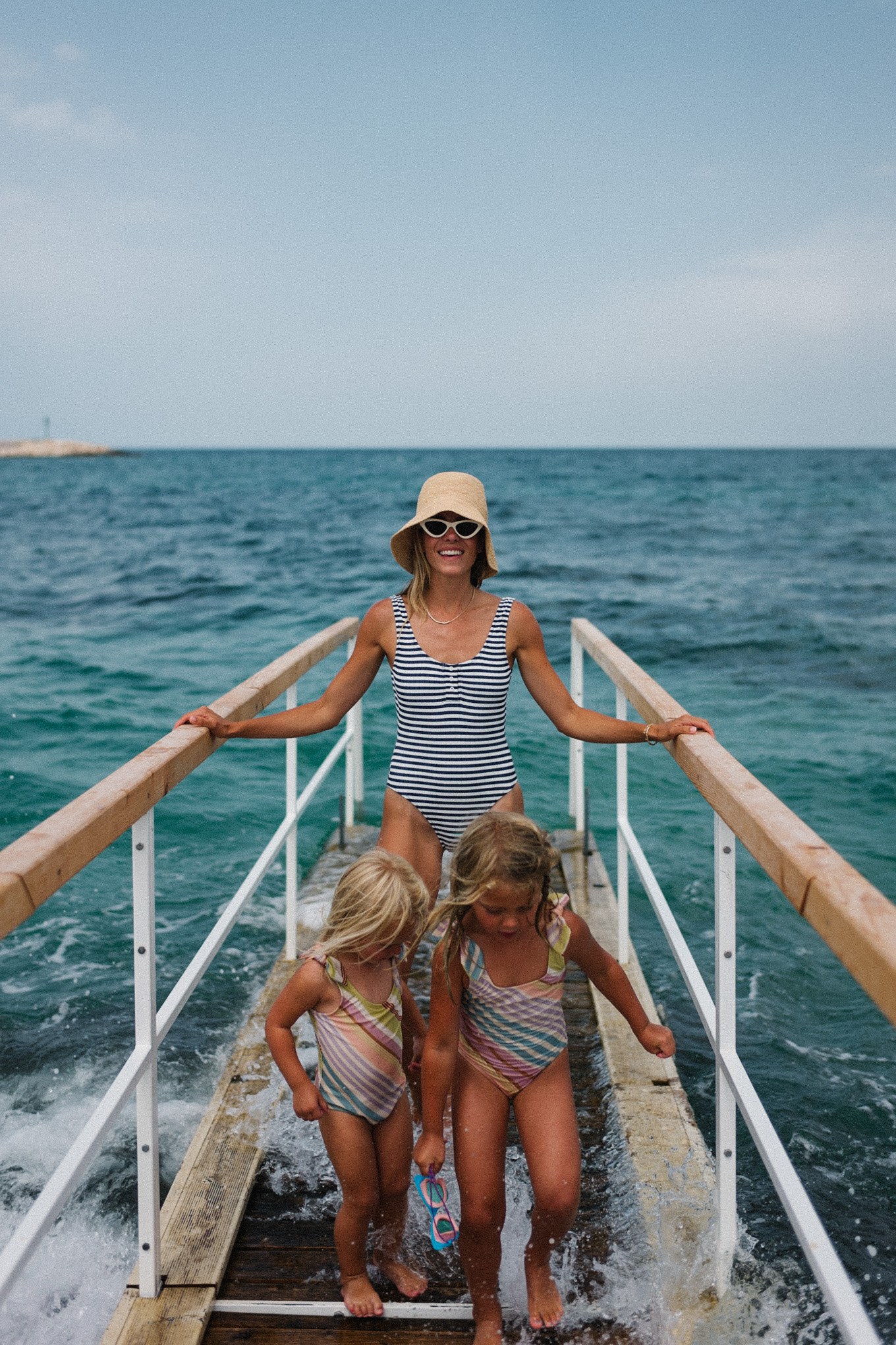 navy white striped swimsuit straw bucket hat white sunglasses