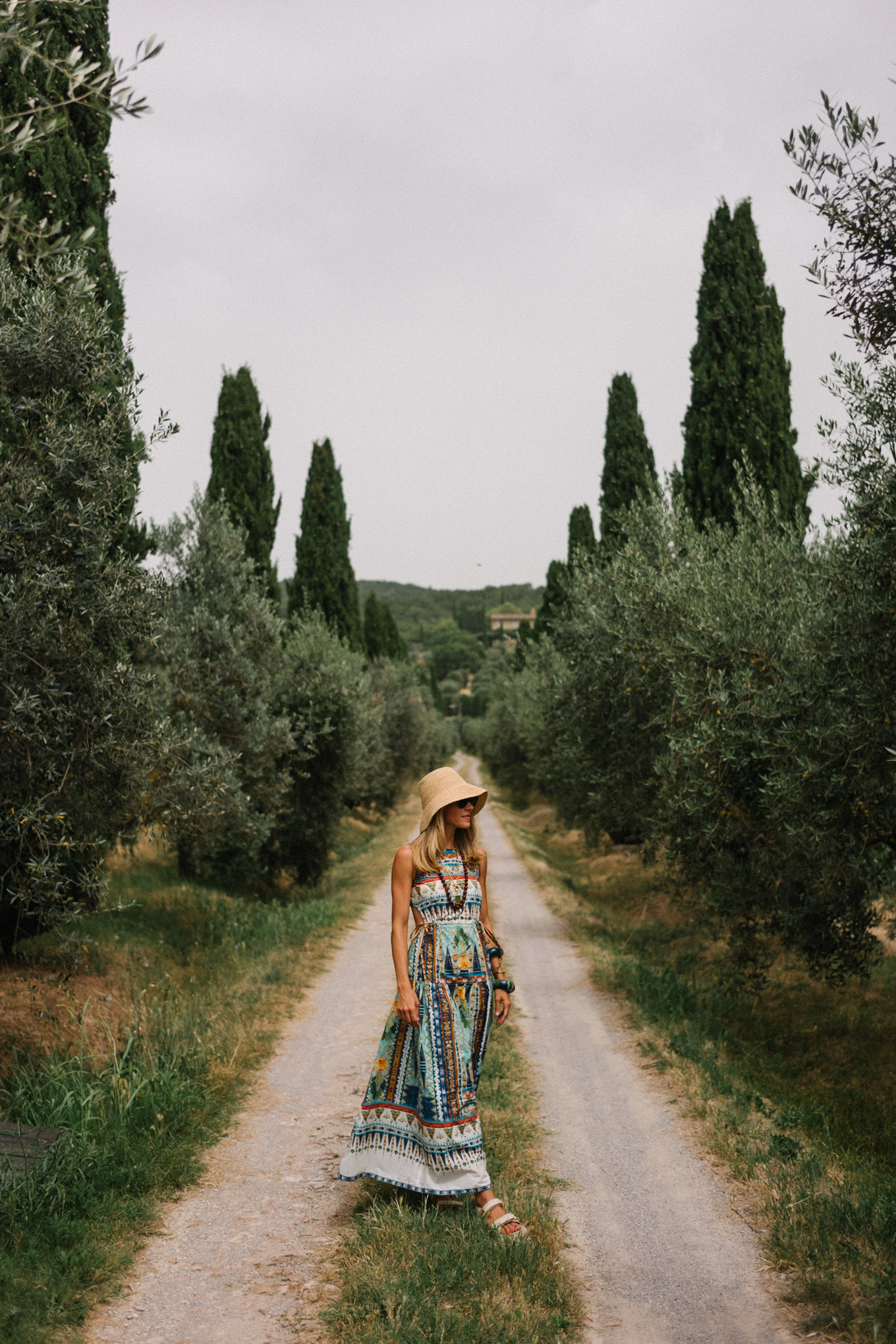 Patterned maxi dress, woven bucket hat, cream sandals, and cream woven bag