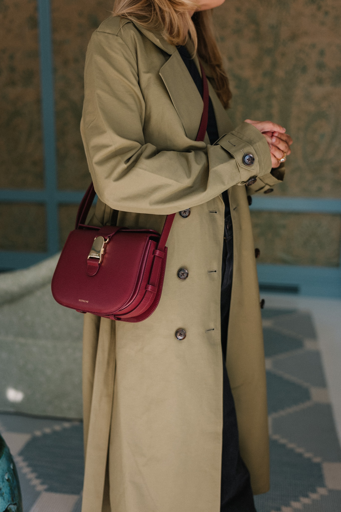 deep khaki trench coat black denim jeans burgundy handbag