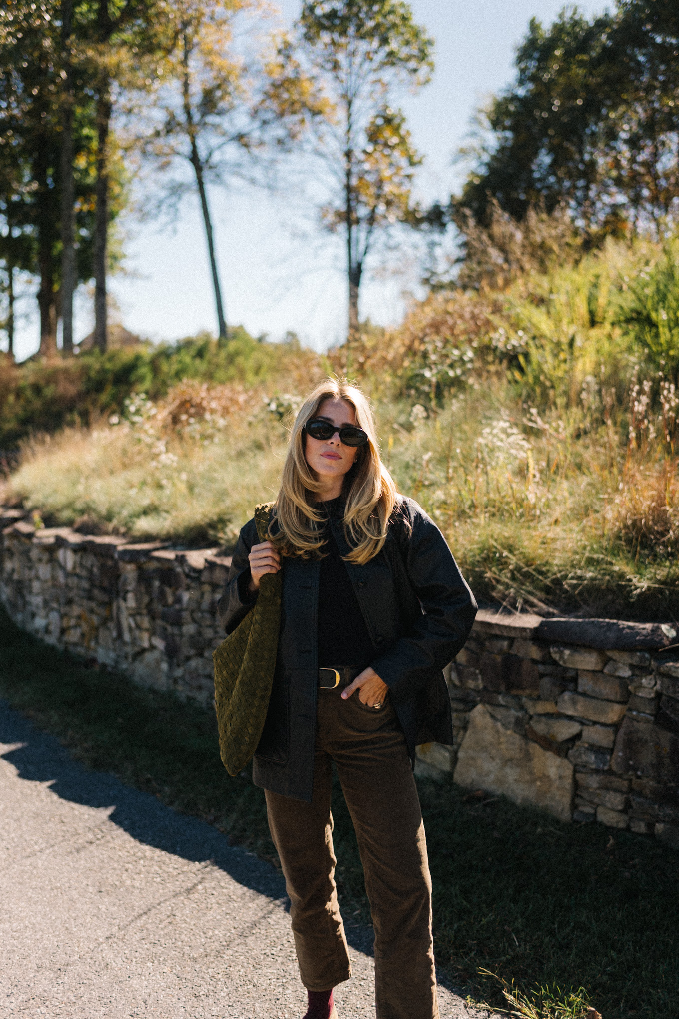 Black leather jacket, black sweater, corduroy trousers, suede bag