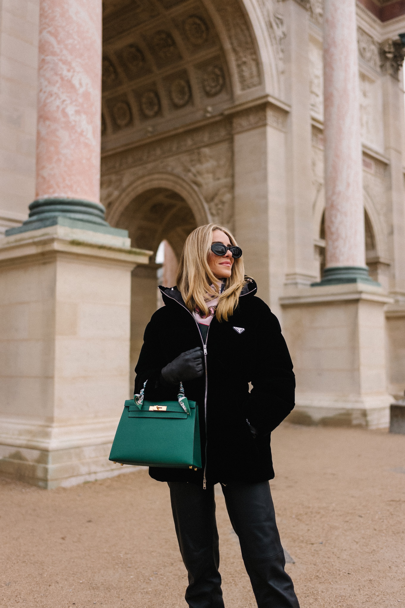 black velvet puffer coat black pants green handbag in paris