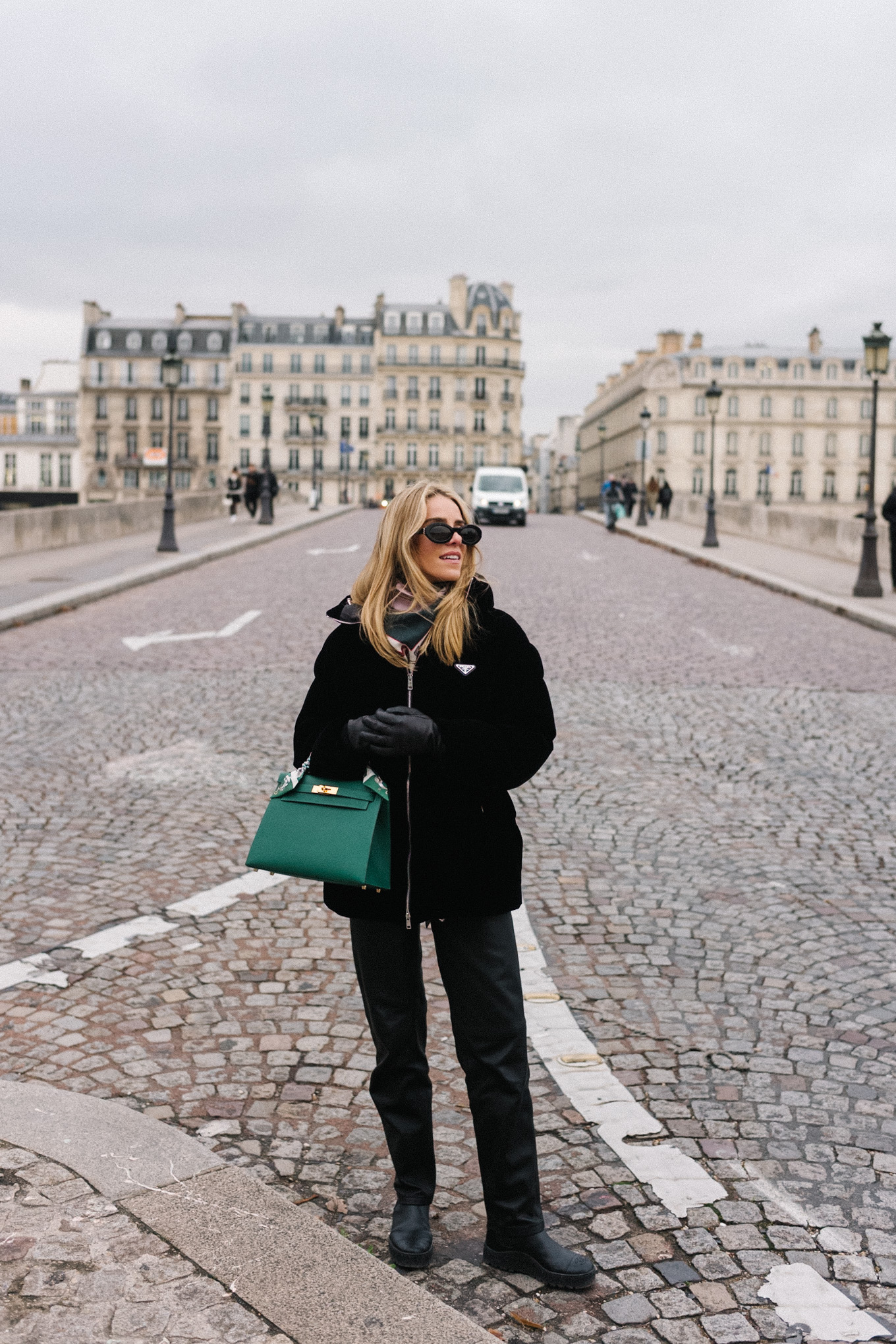 black velvet puffer coat black pants green handbag in paris