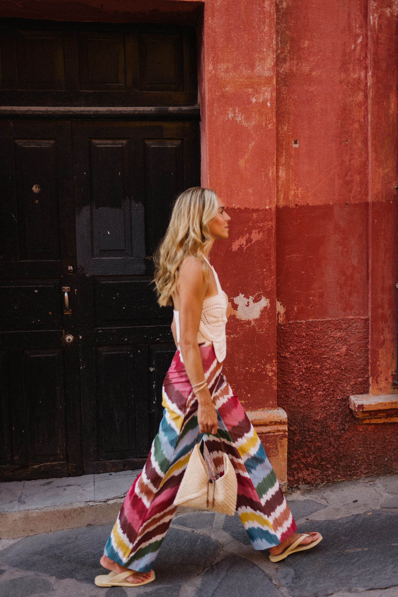 white crochet top rainbow stripe silk pants rattan bag white sandals