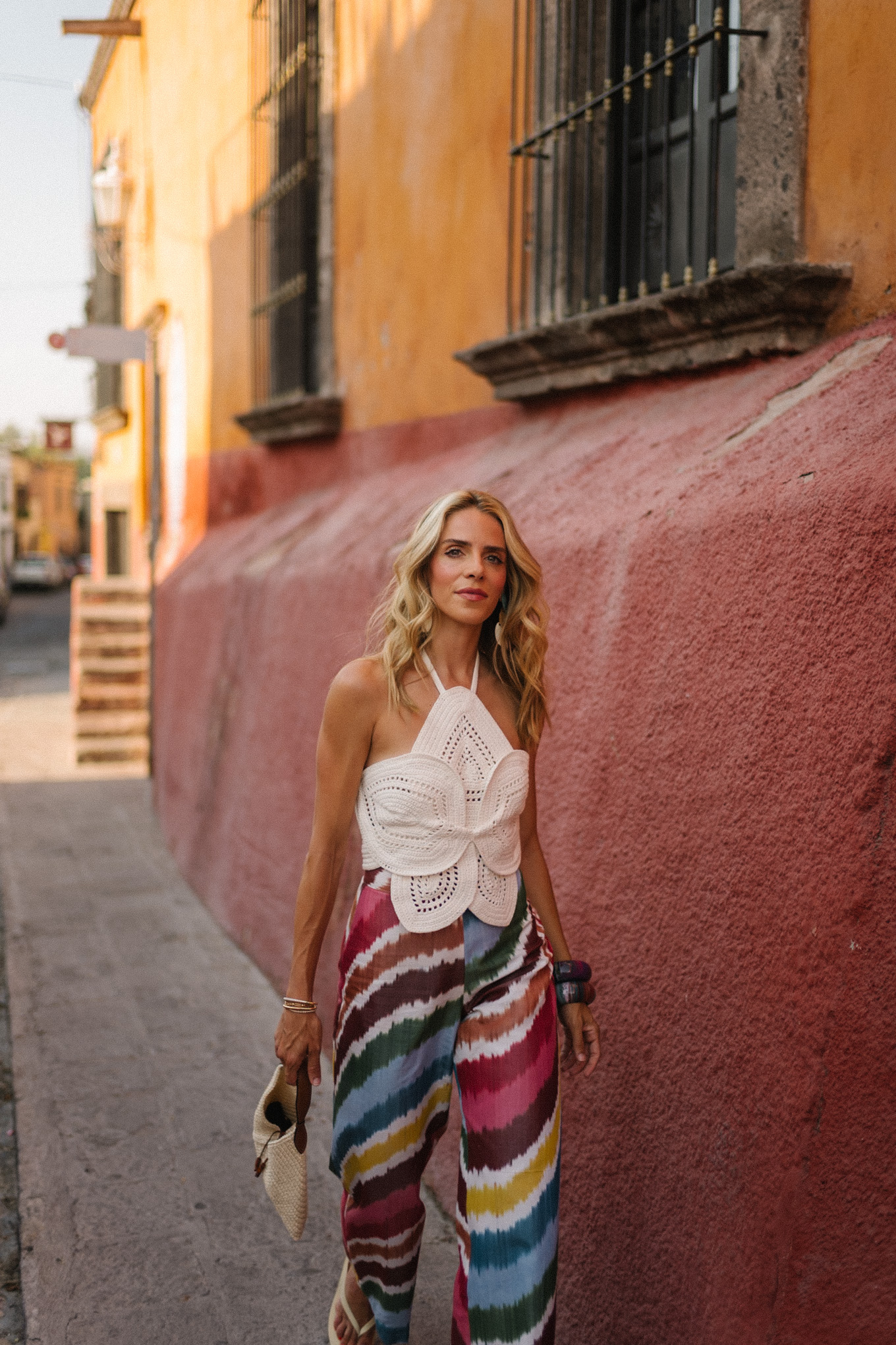 white crochet top rainbow stripe silk pants rattan bag white sandals