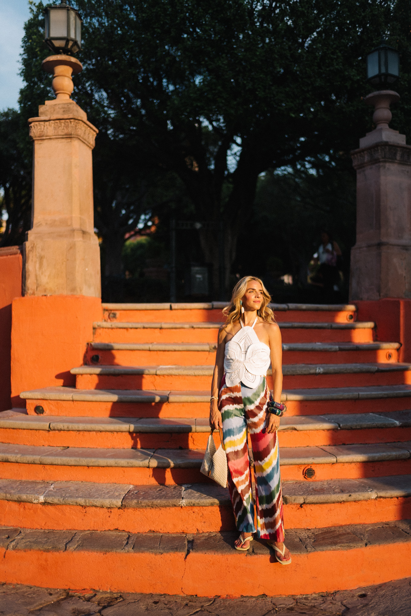 white crochet top rainbow stripe silk pants rattan bag white sandals