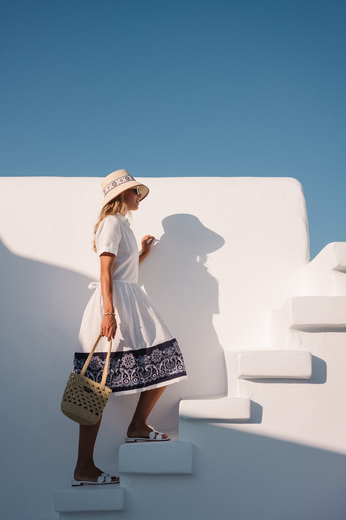 blue white shirtdress straw bucket hat woven bag white heeled sandals