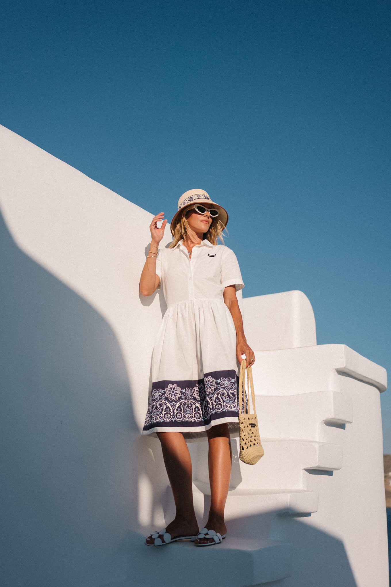 blue white shirtdress straw bucket hat woven bag white heeled sandals