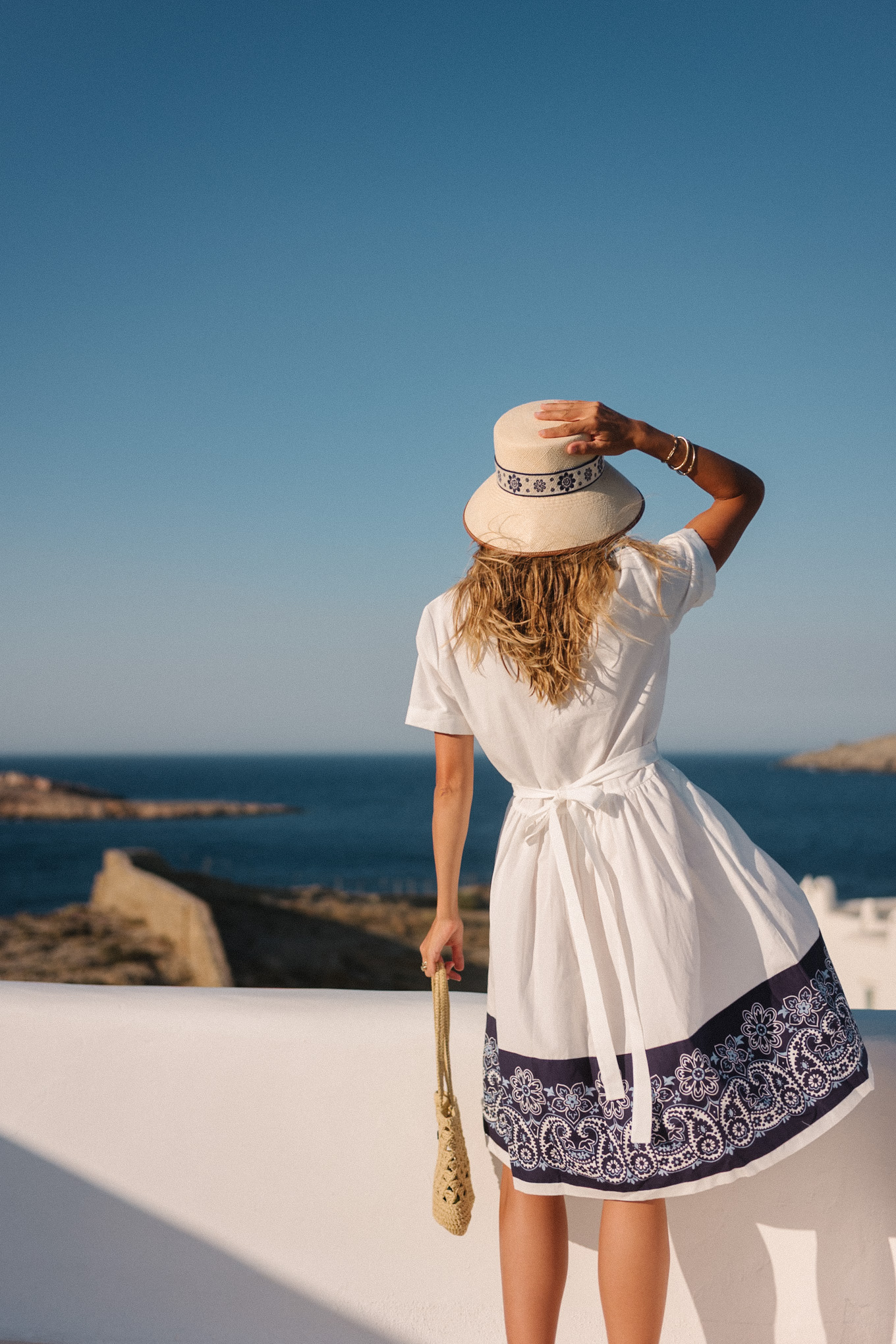blue white shirtdress straw bucket hat woven bag white heeled sandals
