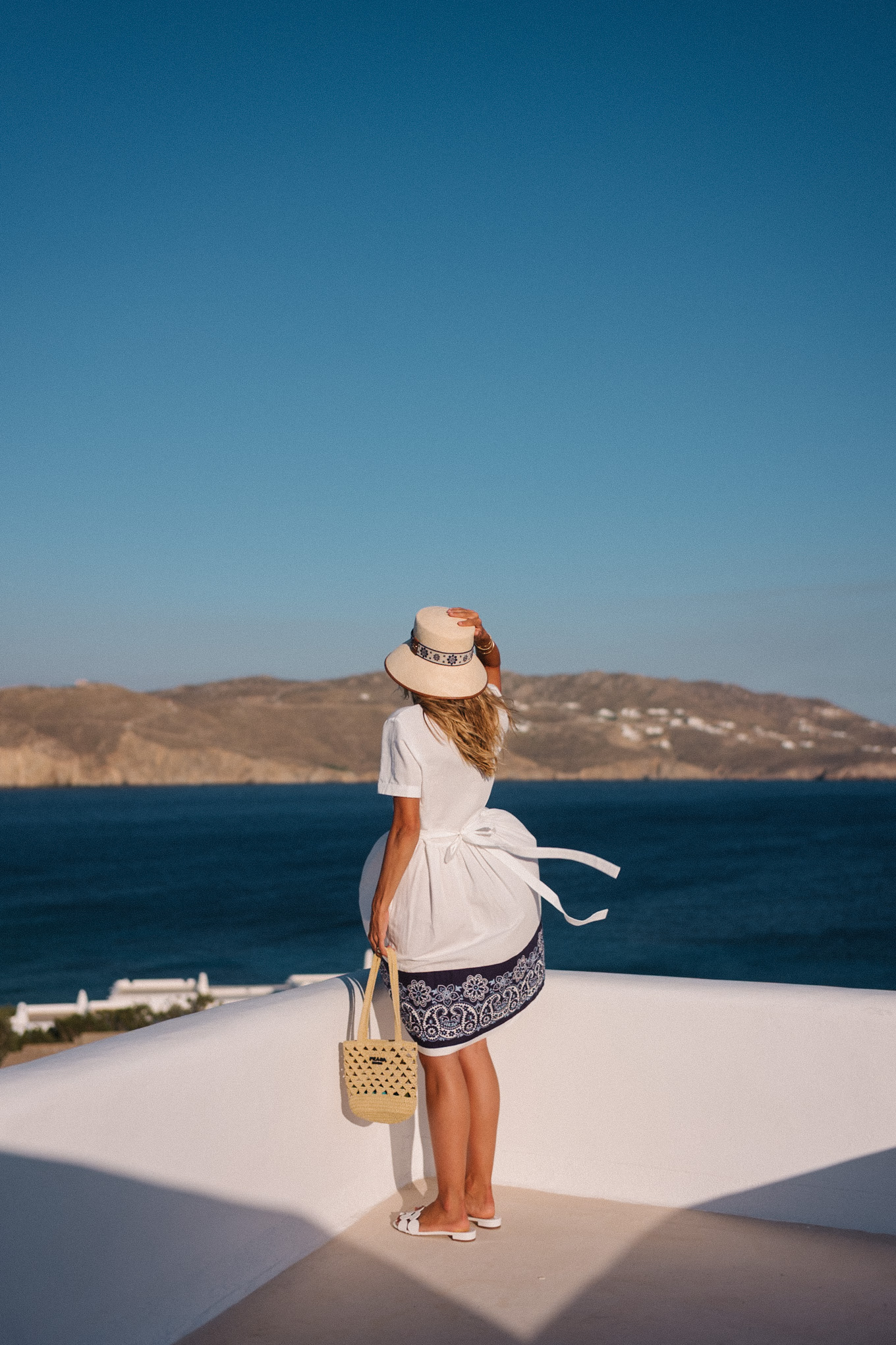 blue white shirtdress straw bucket hat woven bag white heeled sandals
