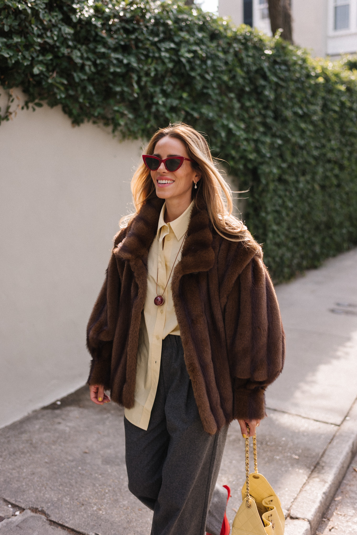 brown faux fur coat yellow button down shirt grey pants yellow tote red flats