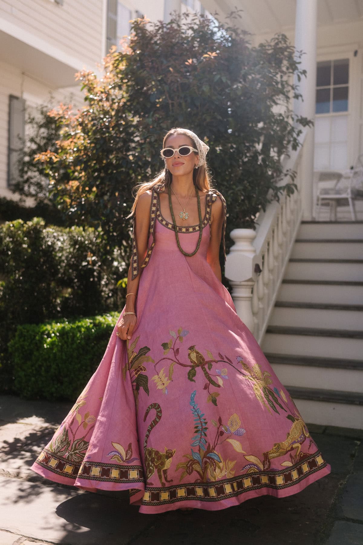 Beautiful woman in pink embroidered boho resort wear with sunglasses and jewelry.